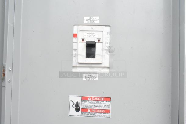 Electrical service disconnect panel with warning labels in English and Spanish about hazardous voltage risks.