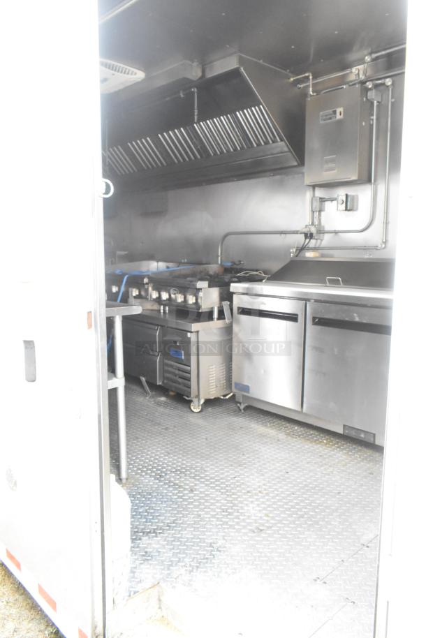 ATX 24' food trailer interior with commercial-grade equipment, grease hood, prep tables, gas range, flat top, and fryers.
