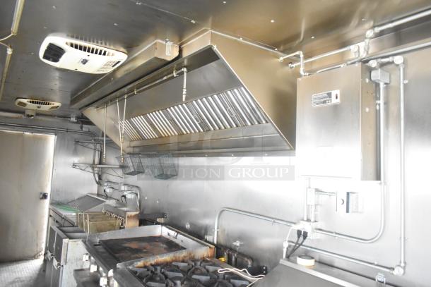 ATX 24' food trailer interior with commercial grease hood, Arctic Air prep tables, Royal gas range, and Frymaster gas fryers.