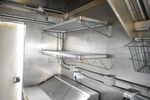 Interior view of an ATX 24' food trailer featuring stainless steel shelving, electrical outlets, and part of a grease hood.