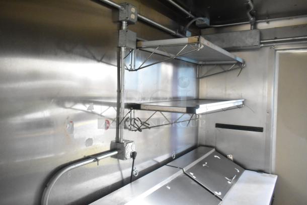 ATX 24' food trailer interior with stainless steel shelves and prep station, commercial-grade setup, new condition.