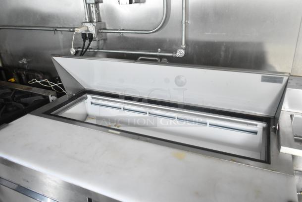 ATX food trailer's Arctic Air prep table open, showing interior. Stainless steel surface, commercial kitchen setup visible.