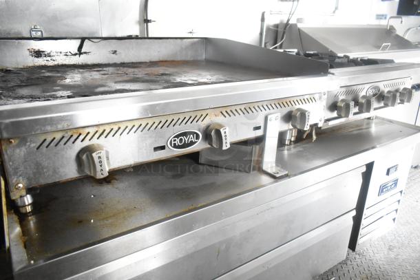 Royal gas flat top grill with multiple knobs in a commercial kitchen trailer. Slight wear visible, integrated into ATX food trailer.