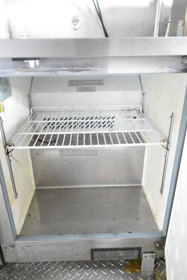 Interior of ATX food trailer with metal shelving and prep area, showcasing space for equipment storage. Clean condition.