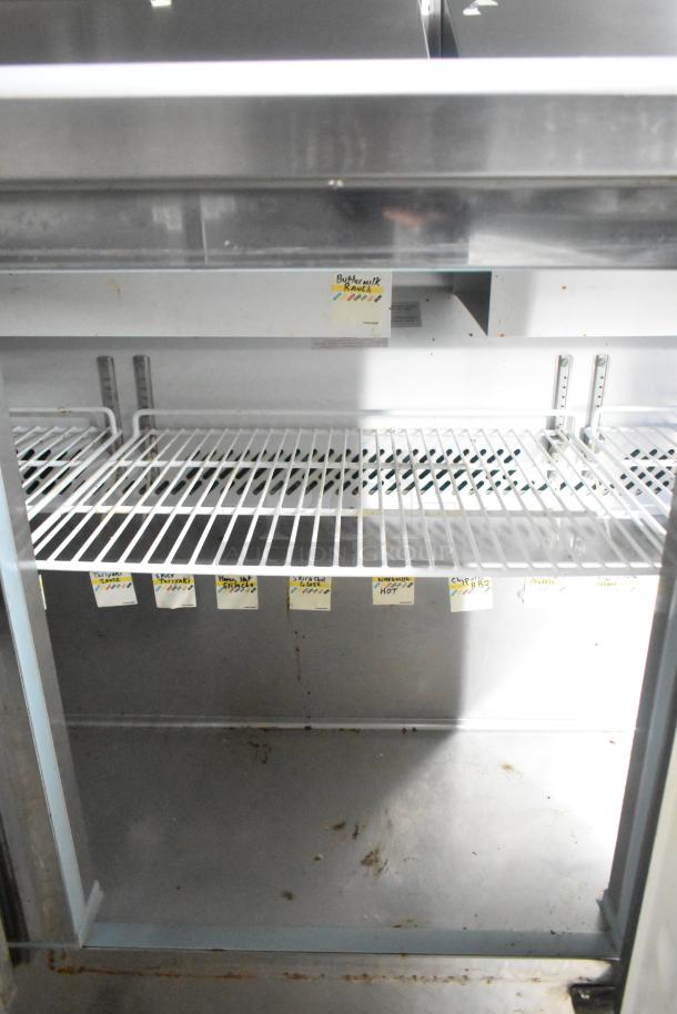 Inside view of an ATX 24' food trailer's refrigeration unit with labeled storage shelves, showing clear organization for sauces.