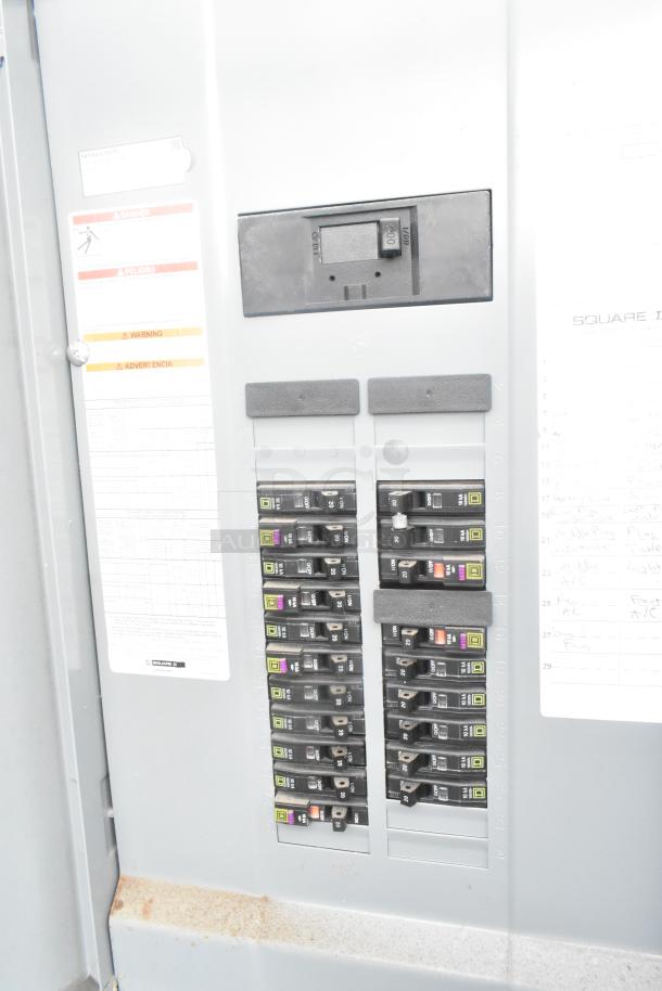Electrical panel with multiple circuit breakers, labels indicating warnings and advisories, part of the ATX food trailer.