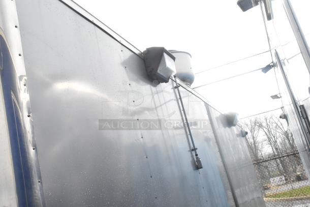 Exterior view of ATX 24' food trailer, featuring stainless steel finish and mounted lighting fixtures.