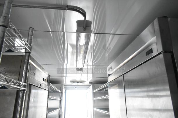 Interior of Southern Dimensions 24' outfitted trailer, featuring stainless steel coolers, shelving units, and overhead lighting.