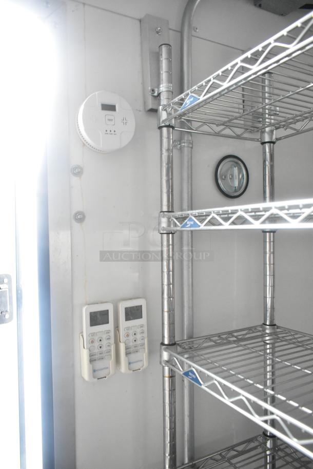 Stainless steel wire shelves and wall-mounted controls inside Southern Dimensions 24' cold food trailer.