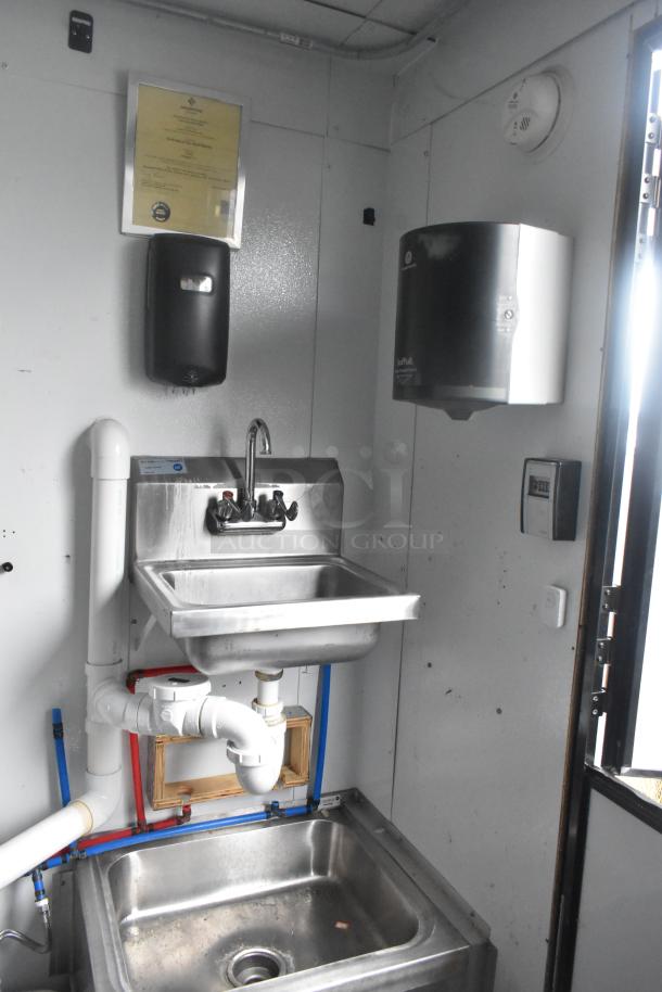 Southern Dimensions 24' trailer interior with stainless steel double sinks, wall-mounted paper towel dispensers, and plumbing beneath.