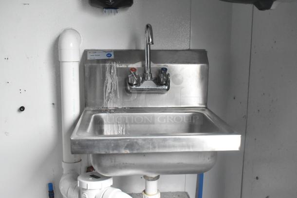 Stainless steel commercial sink with faucet, red and blue handles, installed in a food trailer, NSF label visible.