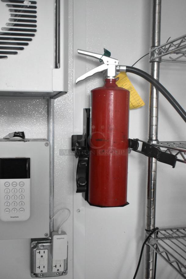 Interior of Southern Dimensions 24' trailer showing wall-mounted fire extinguisher, electrical outlet, and SimpliSafe keypad.