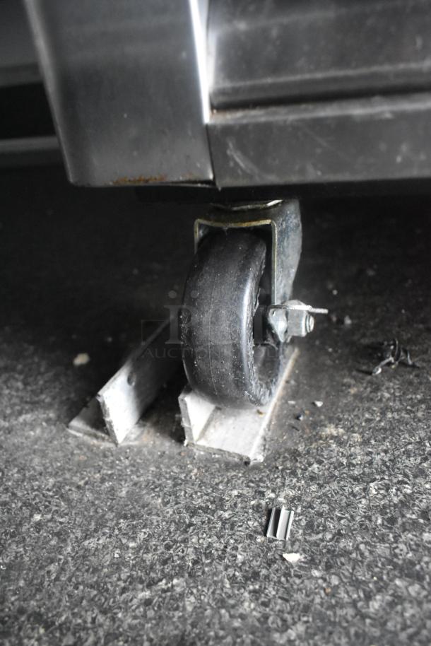 Caster wheel of the Southern Dimensions 24' cold food trailer on textured ground, showing sturdy construction.