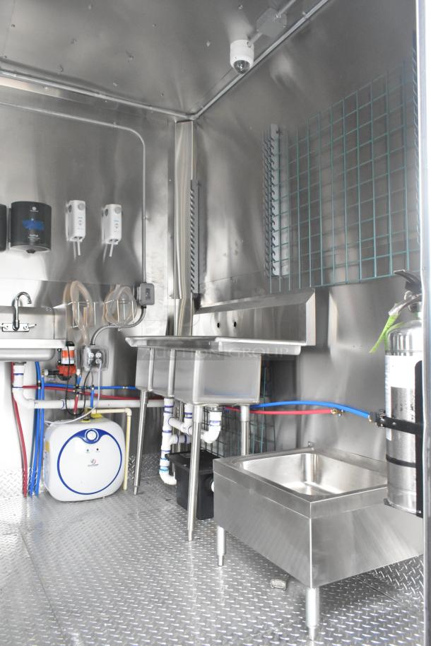 ATX 24' food trailer interior, stainless steel sink, Naks hood, fire suppression, grease trap, and shelving.