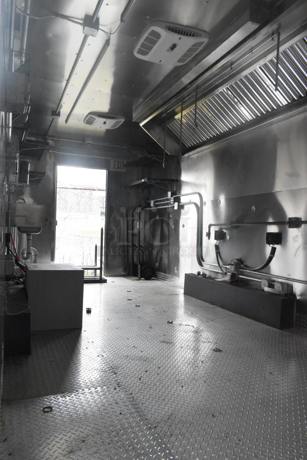 ATX 24' food trailer interior with stainless steel, commercial-grade equipment, grease hood, shelving, and fire suppression system.