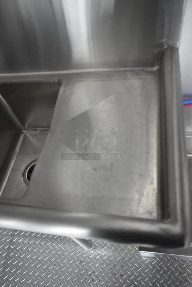 Stainless steel sink inside an ATX 24' food trailer, features a drain and shiny metal finish. Part of a fully equipped mobile kitchen.
