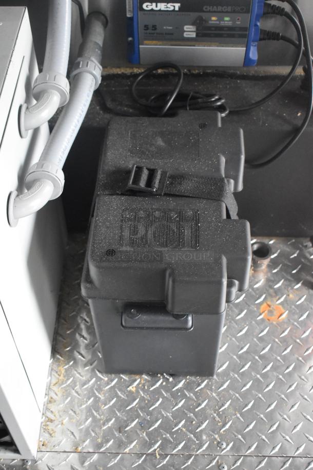 ATX 24' food trailer utility box with pipes and a Guest ChargePro battery charger on diamond plate flooring.