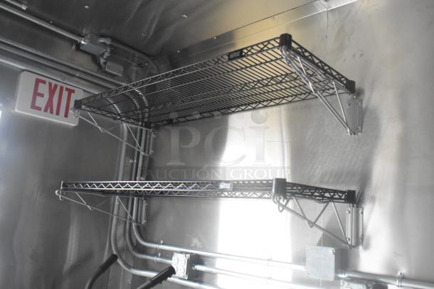 Interior of ATX food trailer with mounted wire shelving and visible EXIT sign, showcasing robust commercial setup.