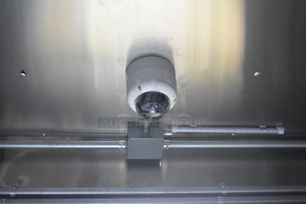 Ceiling-mounted security camera inside an ATX 24' food trailer with metal wiring conduits visible.