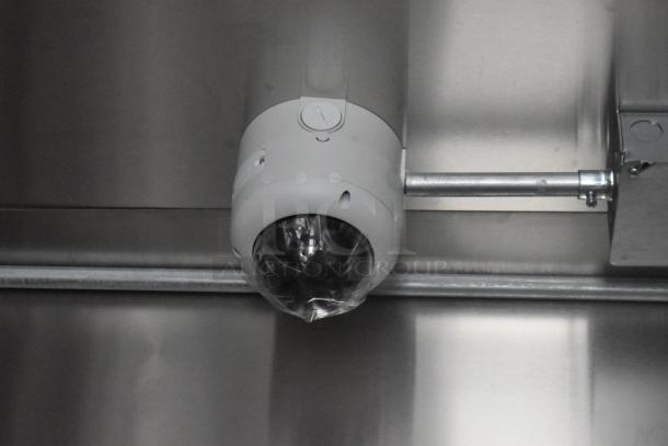 Surveillance camera installed inside a stainless steel food trailer, showing piping and wiring connections.