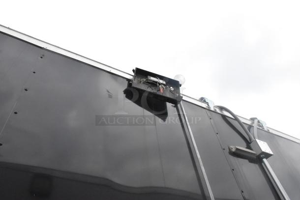 Exterior view of ATX 24' outfitted food trailer, showing electrical connections on a sleek black surface, ideal for mobile kitchen use.