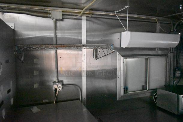 Interior of a Cruising Kitchens 24' food trailer. Features metal shelving, ventilation, and stainless steel surfaces.