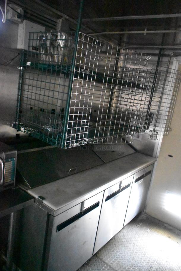 Cruising Kitchens 24' food trailer interior, featuring stainless steel appliances and wire shelving; ready for use.
