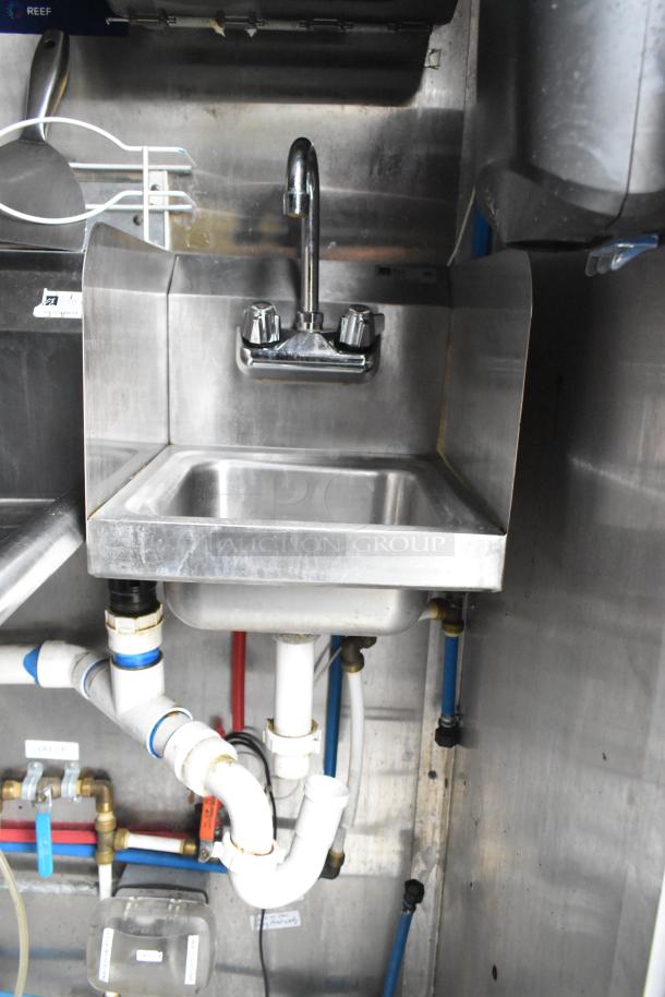 Stainless steel hand sink in a Cruising Kitchens food trailer, including plumbing fixtures and connections.