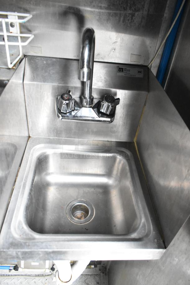 Stainless steel sink with dual-handle faucet in Cruising Kitchens mobile food trailer, NSF certified.