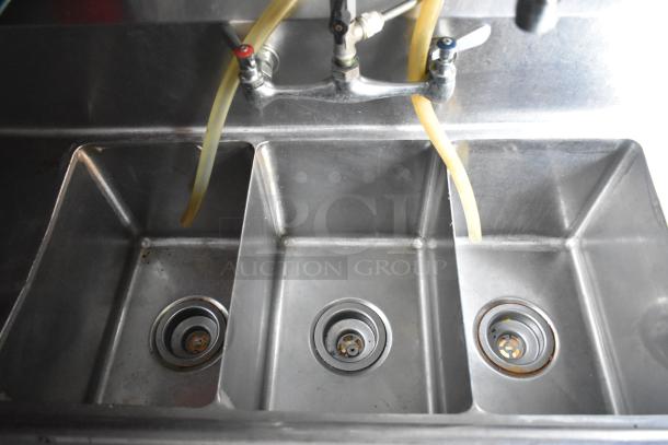 Commercial-grade triple sink in a Cruising Kitchens food trailer, stainless steel, with dual faucet hoses.
