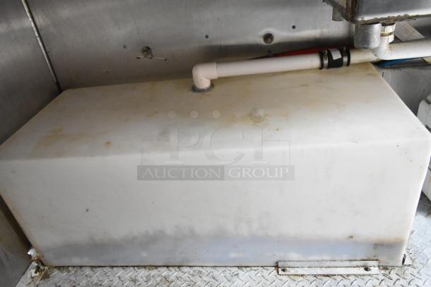 Interior of Cruising Kitchens 24' food trailer showing a mounted, white rectangular storage tank with attached piping.