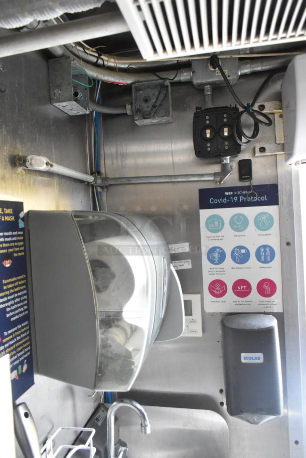 Interior of Cruising Kitchens food trailer with handwashing station, sanitizer dispensers, and safety protocols displayed.