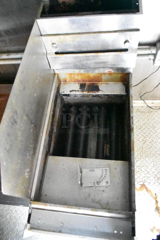 Alt text: "Interior view of a Cruising Kitchens 24' food trailer with stainless steel equipment, showing wear, featuring a grill section."