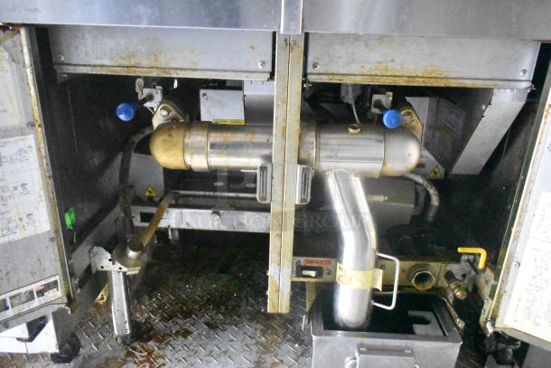 Interior view of a Cruising Kitchens 24' food trailer showing commercial-grade equipment, plumbing, and metal piping.