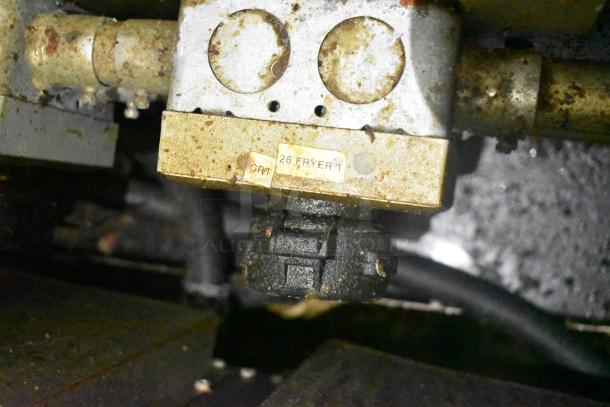 Close-up of a worn fryer control unit with a "26 FRYER 1" label, showing signs of grease and wear, in a food trailer by Cruising Kitchens.