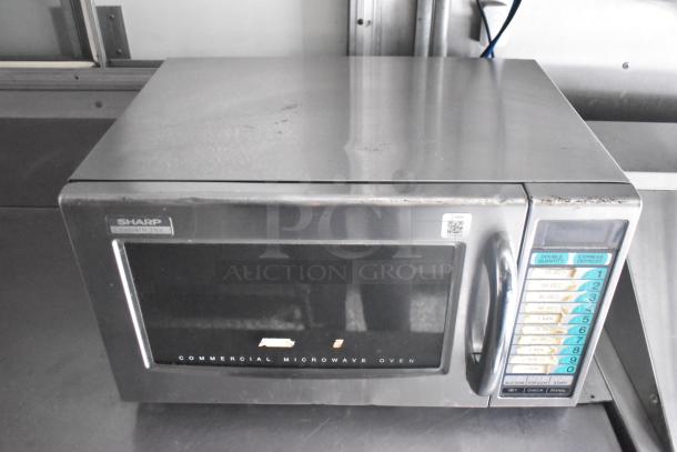Sharp R-21LV commercial microwave oven, 1000W, stainless steel, visible keypad with various cooking options.