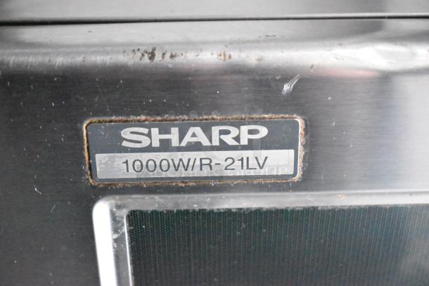 Sharp 1000W R-21LV microwave label, showing some wear, likely part of Cruising Kitchens food trailer equipment setup.