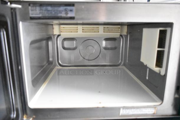 Interior of a commercial-grade microwave inside a Cruising Kitchens mobile food trailer, showing clean stainless steel finish.