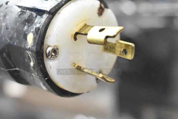 Close-up of a plug connector, potentially for the Wellspring SSI-143S ice cream machine, showing wear and a brass prong.