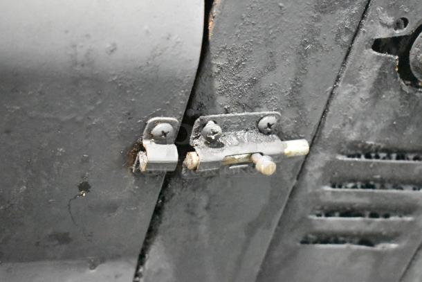 Close-up of an industrial latch on a Blodgett 981 stainless steel commercial pizza oven, showing signs of use.