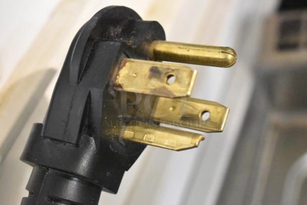 Close-up of a three-pronged electrical plug for the 2022 Lotus CPT-66ET commercial pasta cooker, showing robust brass prongs.