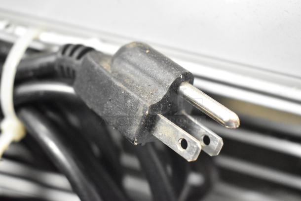 A close-up of a two-prong power plug attached to Cooler Depot LG-1000BF commercial cooler, showing moderate wear.