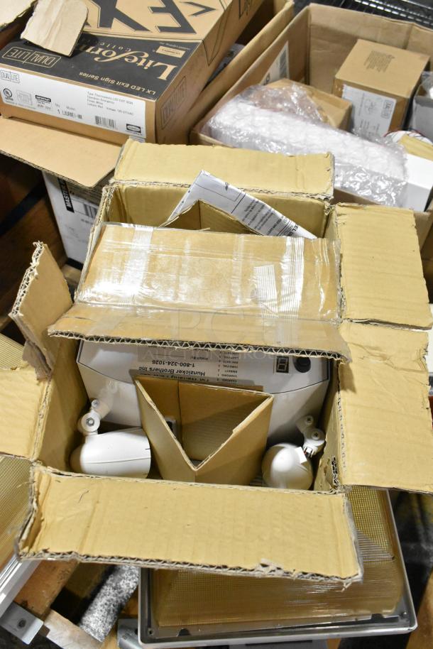 Pallet of various light fixtures, including emergency lights. Boxes with labels visible, indicating a mix of new and gently used items.