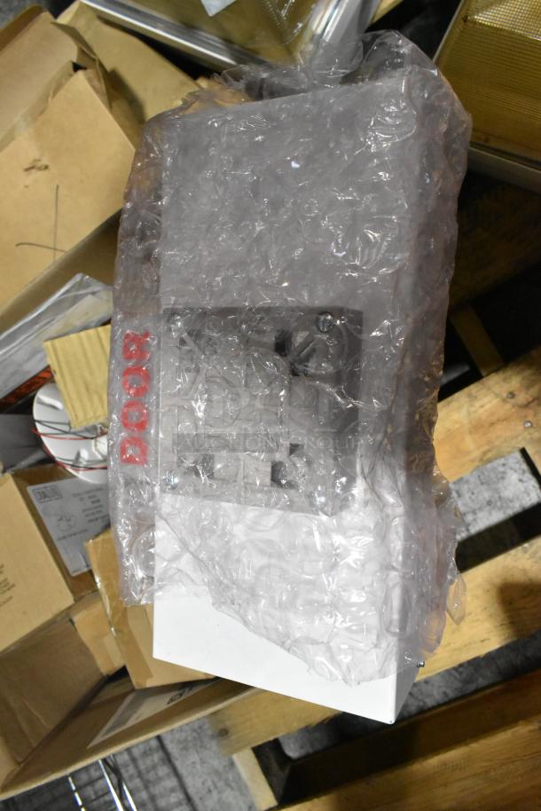 Pallet lot of various light fixtures wrapped in bubble wrap, including an emergency light, resting on a wood pallet.