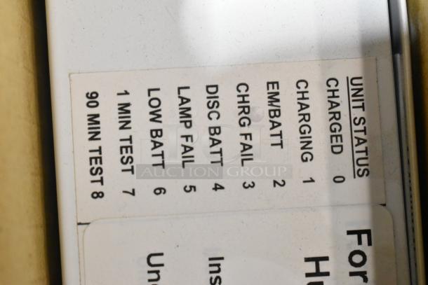 Label on a light fixture indicating unit status with various conditions such as "Charged" and "Low Batt." Key testing indicators like "1 Min Test" and "90 Min Test" are also visible.