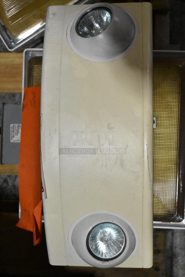 Pallet of various light fixtures including an emergency light, beige casing, dual round lamps; used condition.