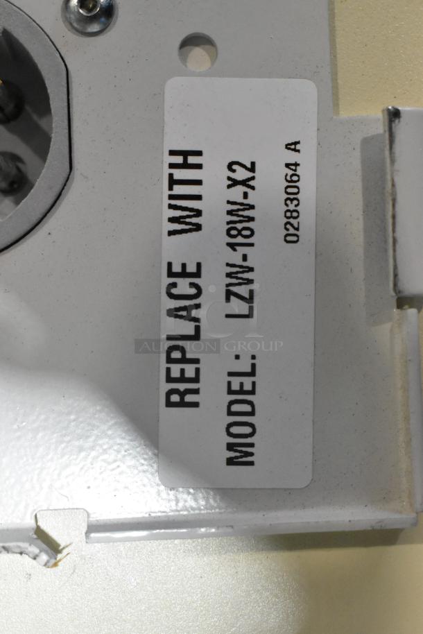 Pallet of various light fixtures including an emergency light. Label on fixture indicates model replacement: LZW-18W-X2.