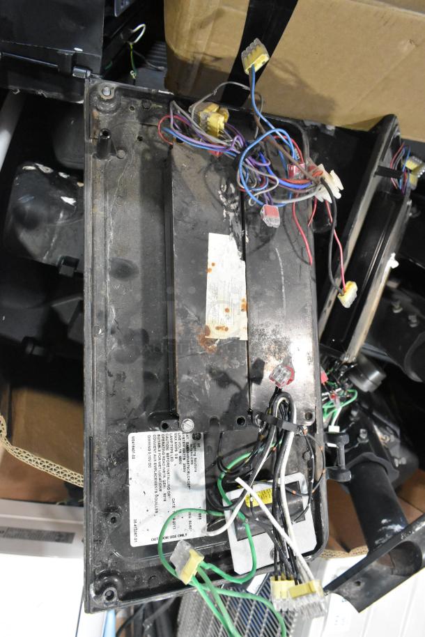 Pallet of various items, including outdoor light fixtures with exposed wiring and visible wear, labels indicate electrical specs.