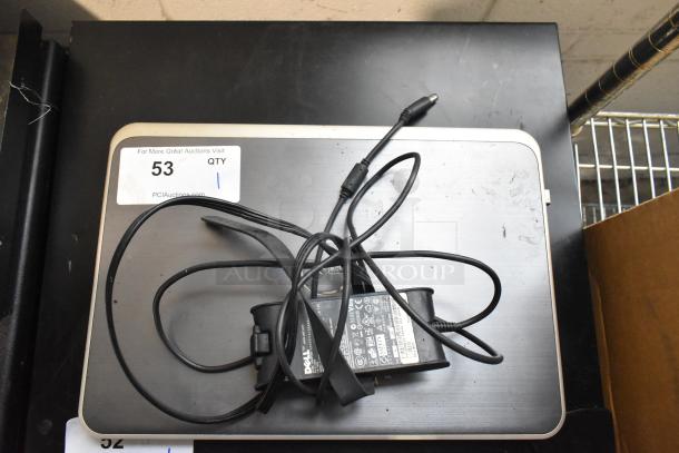 Dell Inspiron 15R-5537 laptop with charger on a table. Visible label indicates auction item number 53.