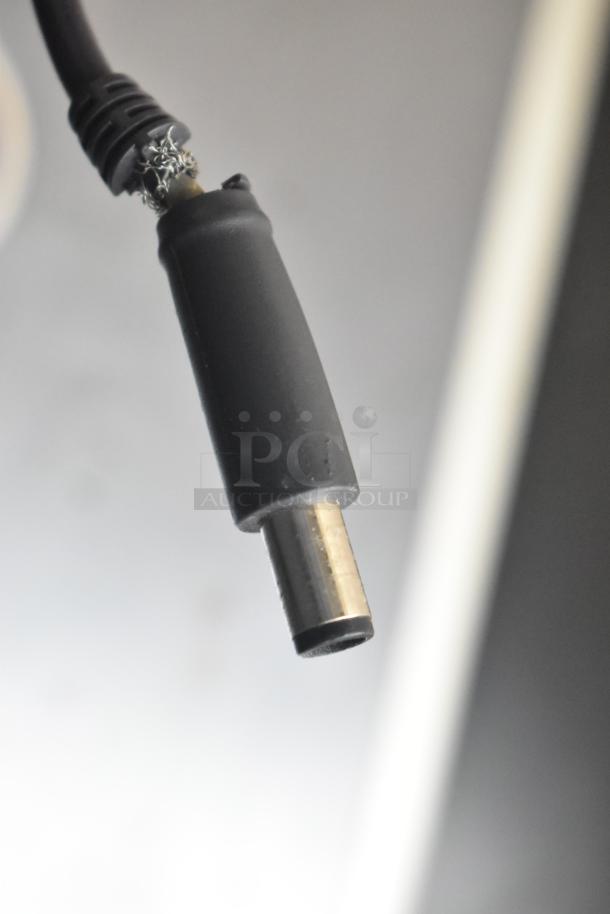 Close-up of a Dell Inspiron 15R-5537 laptop charger plug. Plug shows wear with some exposed wiring.